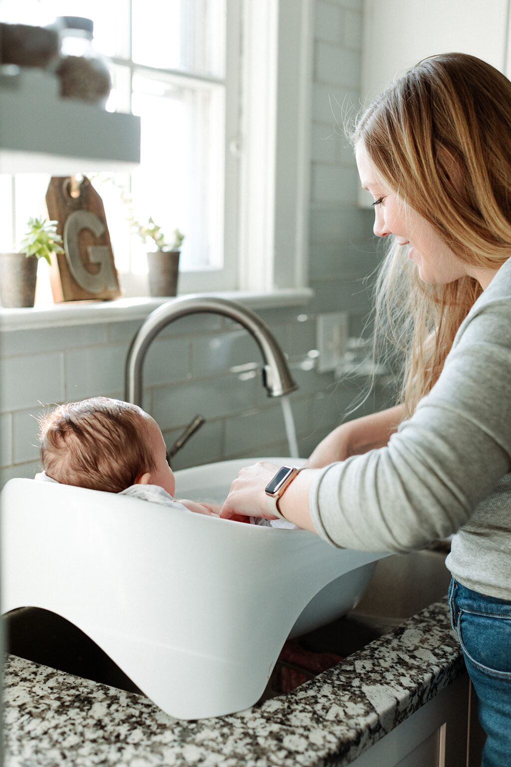 woman bathes baby in sink