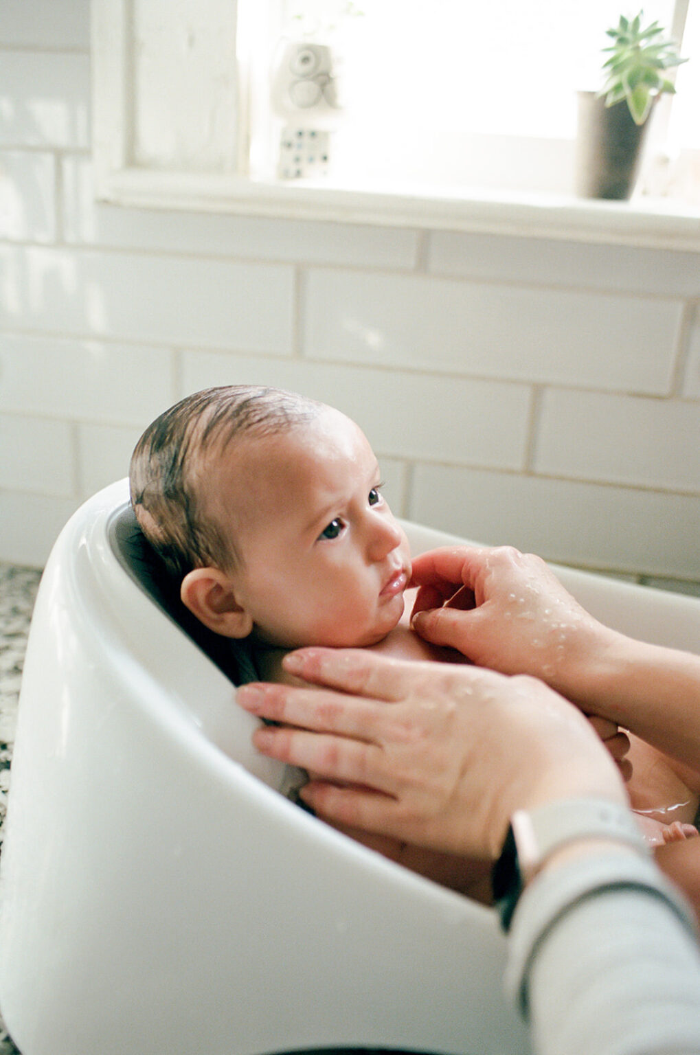 woman bathes baby in sink